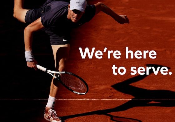 Jannik Sinner serving on a clay court in a promo for Allianz