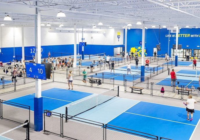 Pickleball Kingdom's state-of-the-art indoor facility features professional-grade courts, digital scoreboards, and dedicated court-side seating, creating a premium experience for players of all skill levels.